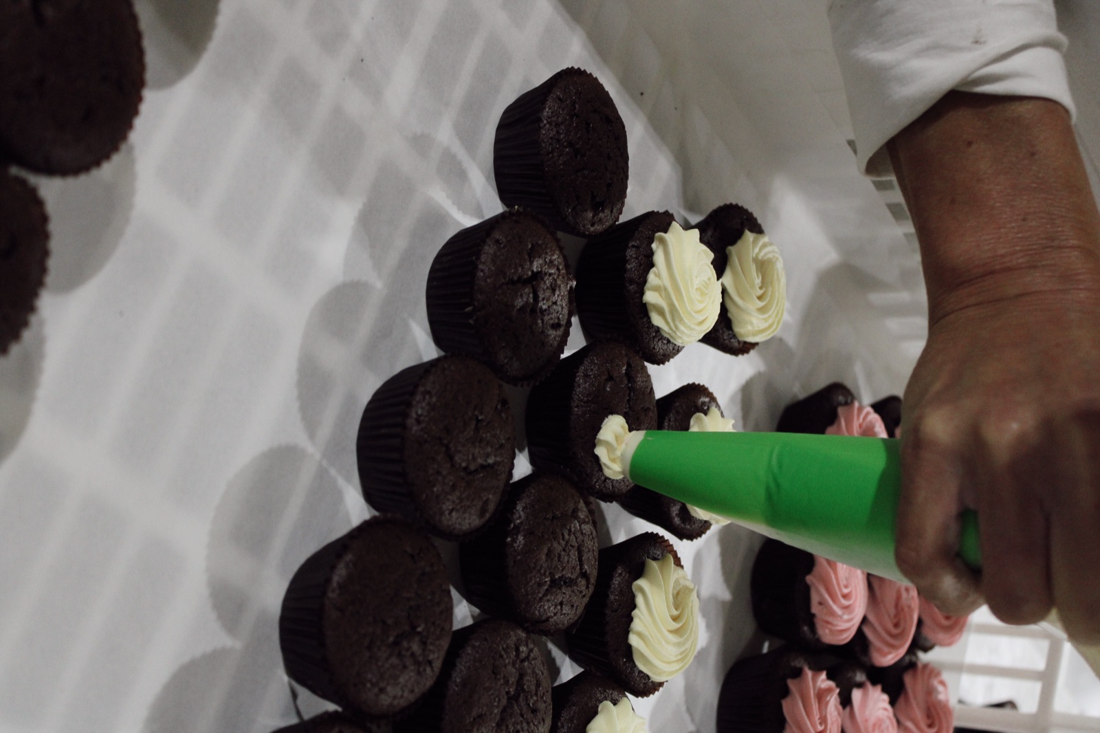 Baker piping cream onto chocolate cupcakes at Knotts Bakery
