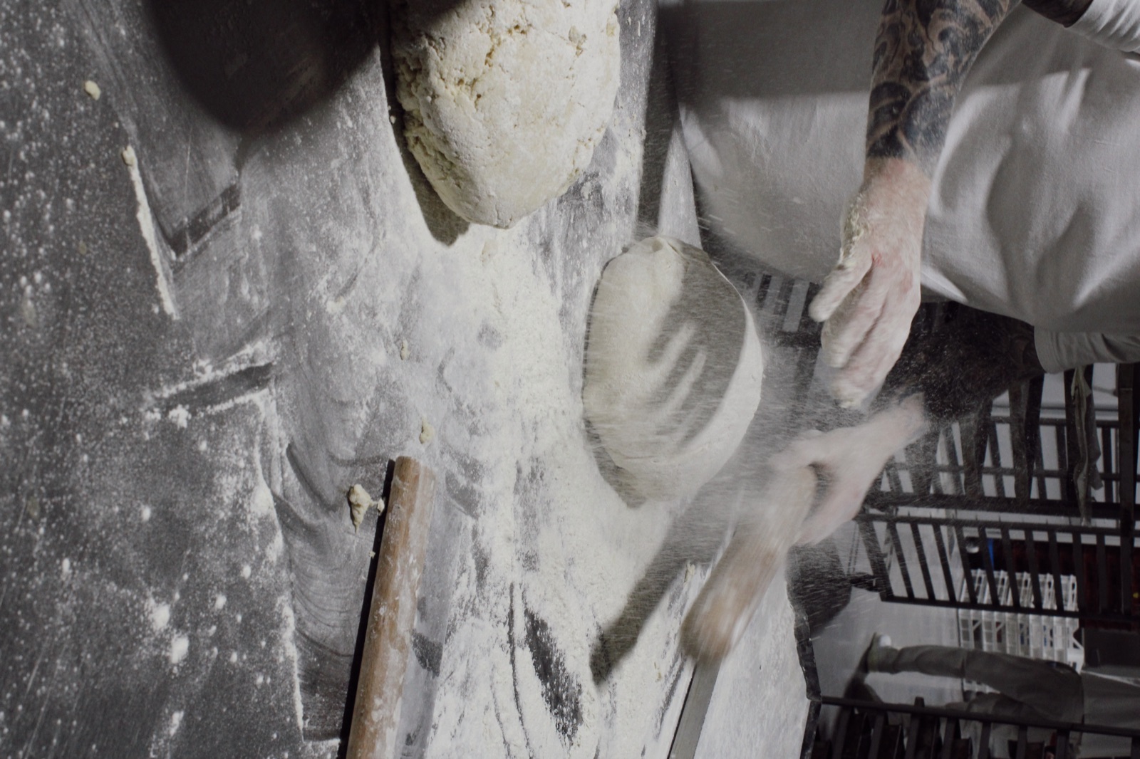 Baker dusting bread dough with flour at Knotts Bakery